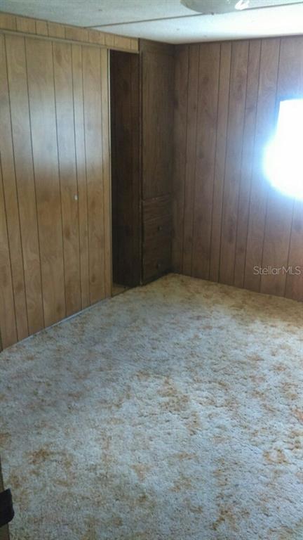 A bedroom features wood-paneled walls, a built-in closet with drawers, and beige carpet — 805 PETERS STREET, WILDWOOD, FL