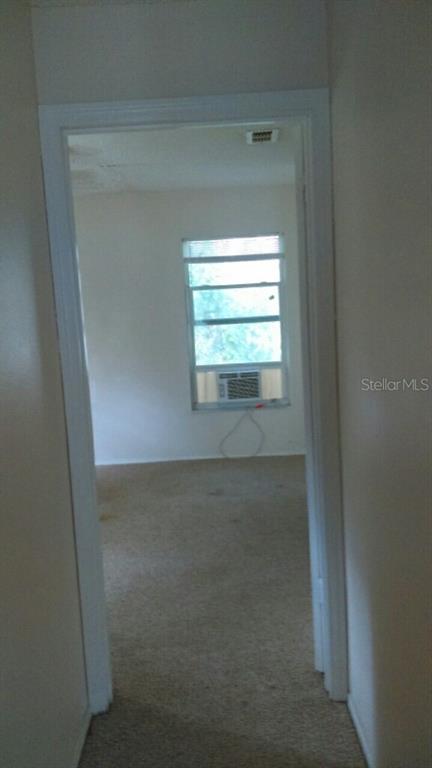 A view through a doorway into a carpeted room with a window-mounted air conditioning unit — 805 PETERS STREET, WILDWOOD, FL