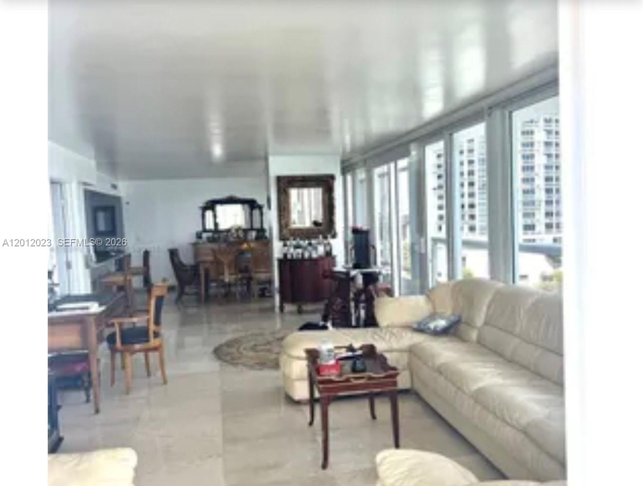A living room features light tile floors, a white sectional sofa, and floor-to-ceiling windows — 1717 N Bayshore Dr # 1734, Miami FL 33132, MIAMI, FL