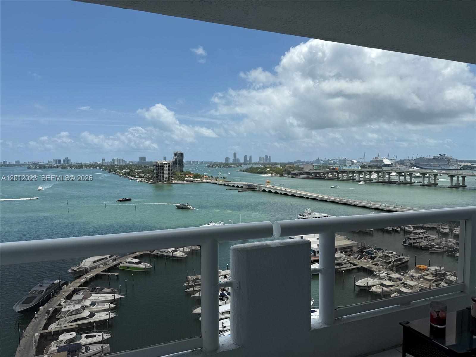 A balcony overlooks a marina, a bridge, and a distant city skyline under a cloudy sky — 1717 N Bayshore Dr # 1734, Miami FL 33132, MIAMI, FL
