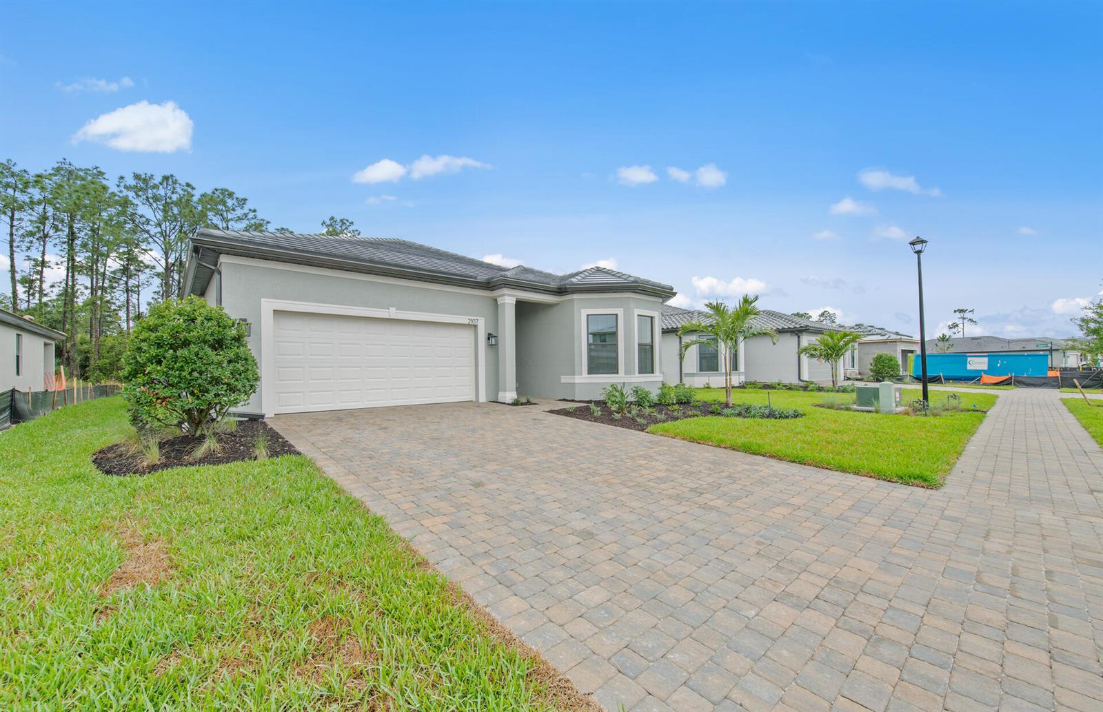 A single-story house with a gray stucco exterior, a two-car garage, and a paver driveway — 2107 Freemont Drive, Naples FL 34120, NAPLES, FL