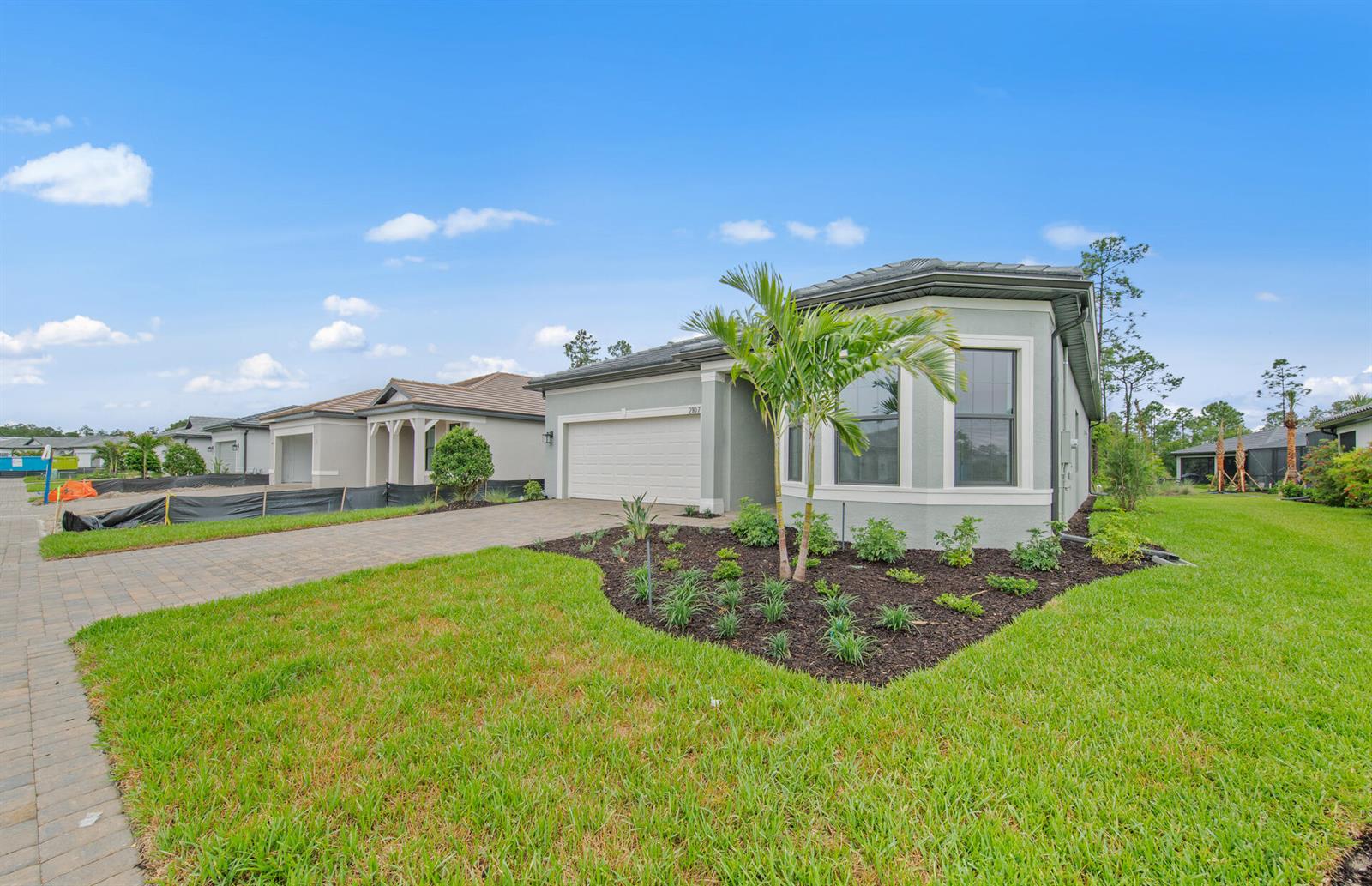 A single-story house with a paved driveway, a palm tree, and landscaped garden beds — 2107 Freemont Drive, Naples FL 34120, NAPLES, FL