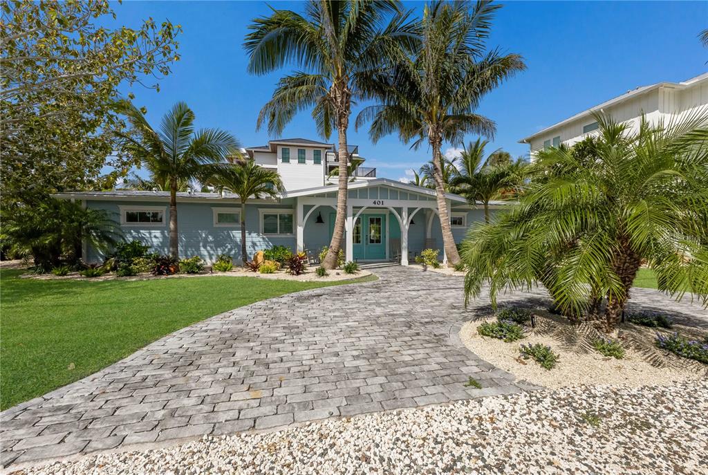 A light blue house with a paved driveway and palm trees under a clear sky — 401 N SHORE DRIVE, ANNA MARIA, FL