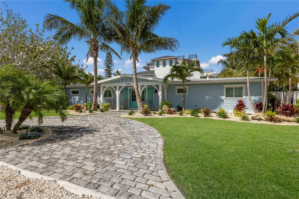 A light blue house with a paved driveway and palm trees under a clear sky — 401 N SHORE DRIVE, ANNA MARIA, FL