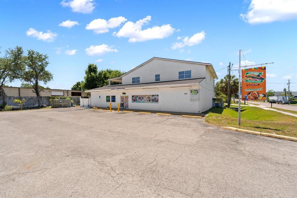 A two-story commercial building with a large paved parking lot under a blue sky — 4624 N HUBERT AVENUE, TAMPA, FL