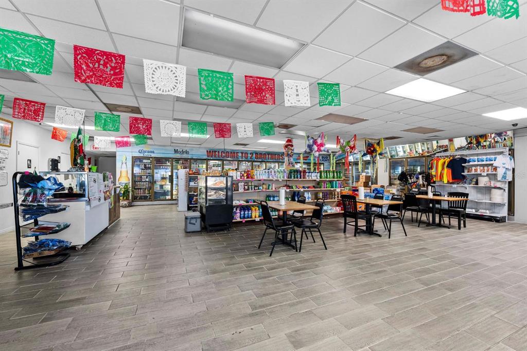 A retail store interior features tiled floors, drop ceilings with festive banners, and dining tables — 4624 N HUBERT AVENUE, TAMPA, FL