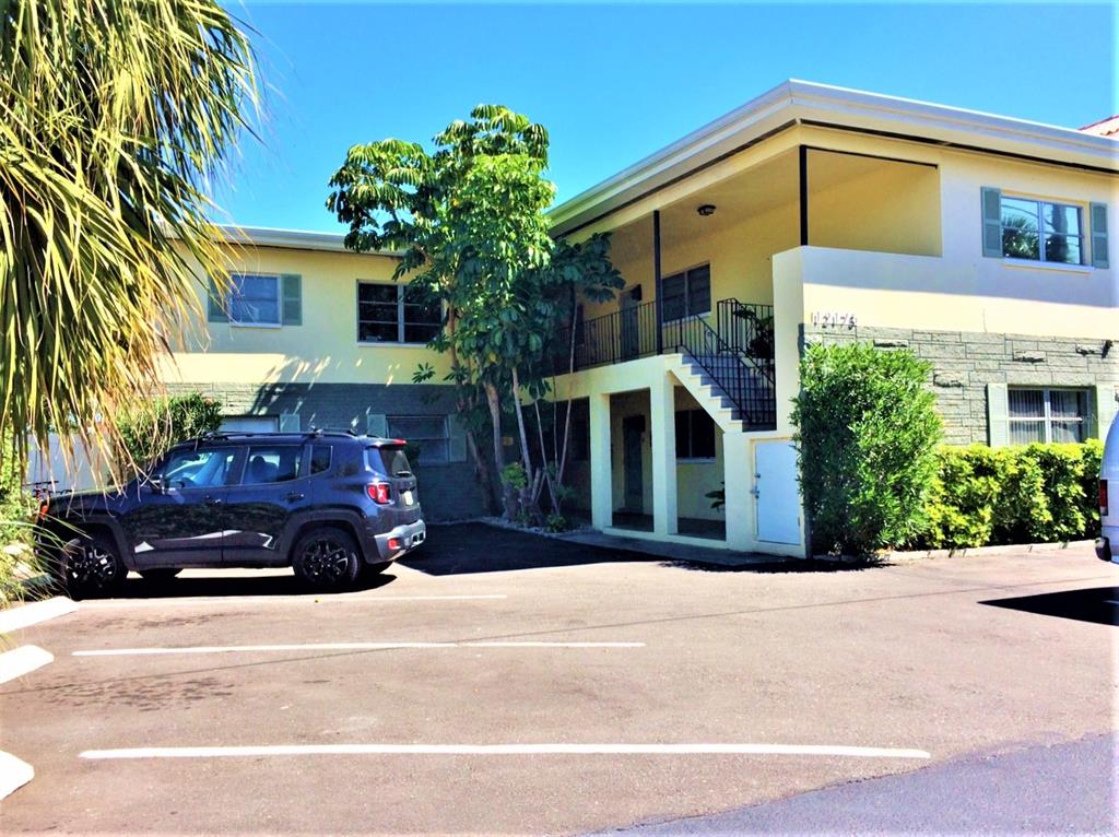 A two-story apartment building with a parking lot, palm tree, and exterior staircase — 12175 3RD STREET E UNIT 2, TREASURE ISLAND, FL
