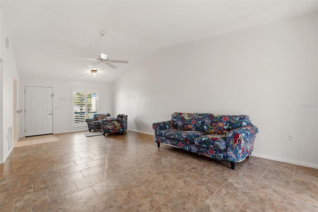 A living room with white walls, tile flooring, a ceiling fan, and patterned furniture — 6132 29TH AVENUE W UNIT 6132, BRADENTON, FL