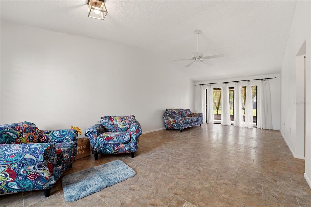 A living room with tile flooring, white walls, a ceiling fan, and patterned furniture — 6132 29TH AVENUE W UNIT 6132, BRADENTON, FL