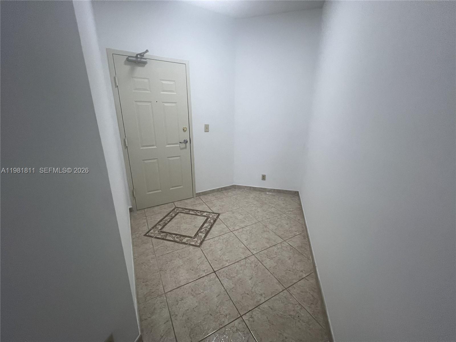 An entryway features a beige door, white walls, and light-colored tile flooring — 8816 Collins Ave # 105, Surfside FL 33154, SURFSIDE, FL