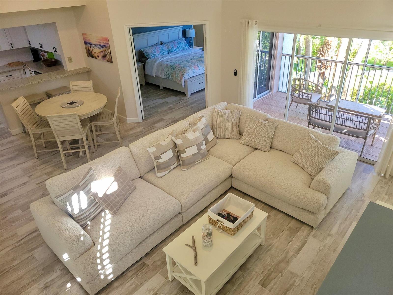 An elevated view of a living room with a sectional sofa, dining area, and balcony — 3108 Fairway Drive N, Jupiter FL 33477, JUPITER, FL