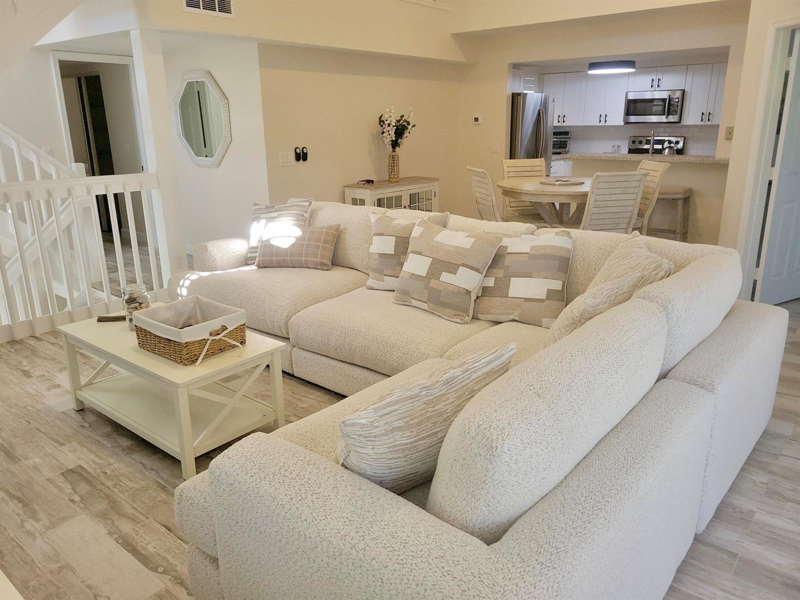 A bright living room features a large white sectional sofa, coffee table, and open kitchen — 3108 Fairway Drive N, Jupiter FL 33477, JUPITER, FL
