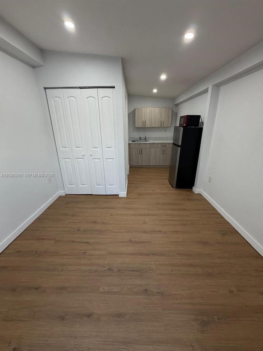 This room features light wood-look flooring, white walls, a closet, and a small kitchenette — 19360 SW 116th Ave # 0, Miami FL 33157, MIAMI, FL