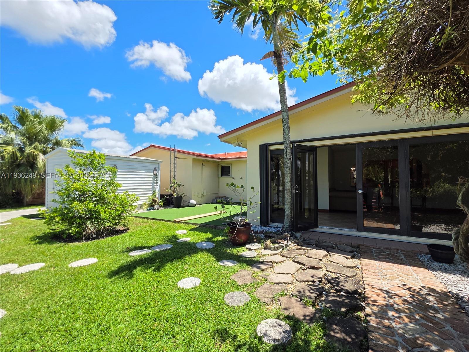 A backyard features a stone path, a green lawn, a shed, and a house exterior — 14545 SW 75th St, Miami FL 33183, MIAMI, FL
