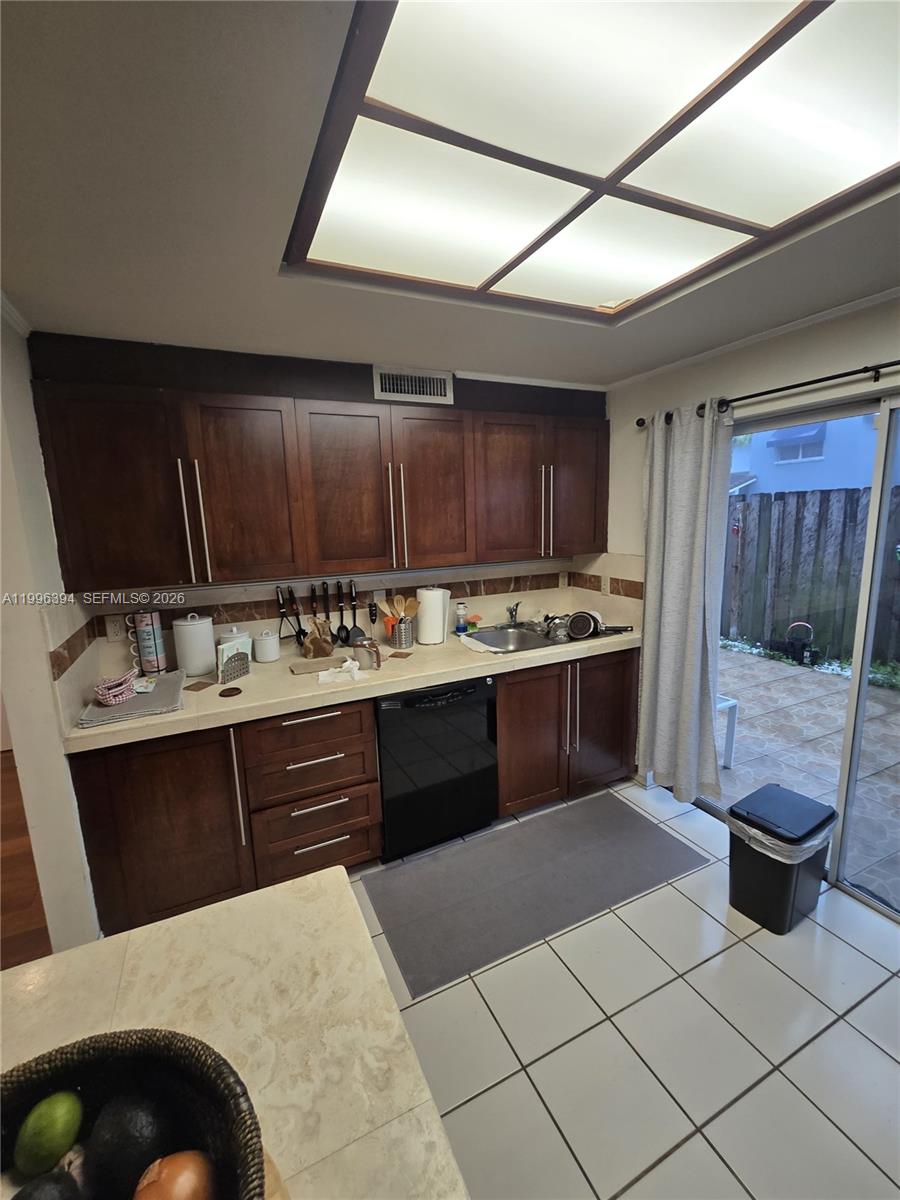 A kitchen features dark wood cabinets, a black dishwasher, and a sliding glass door — 7010 NW 173rd Dr # 1901, Hialeah FL 33015, HIALEAH, FL