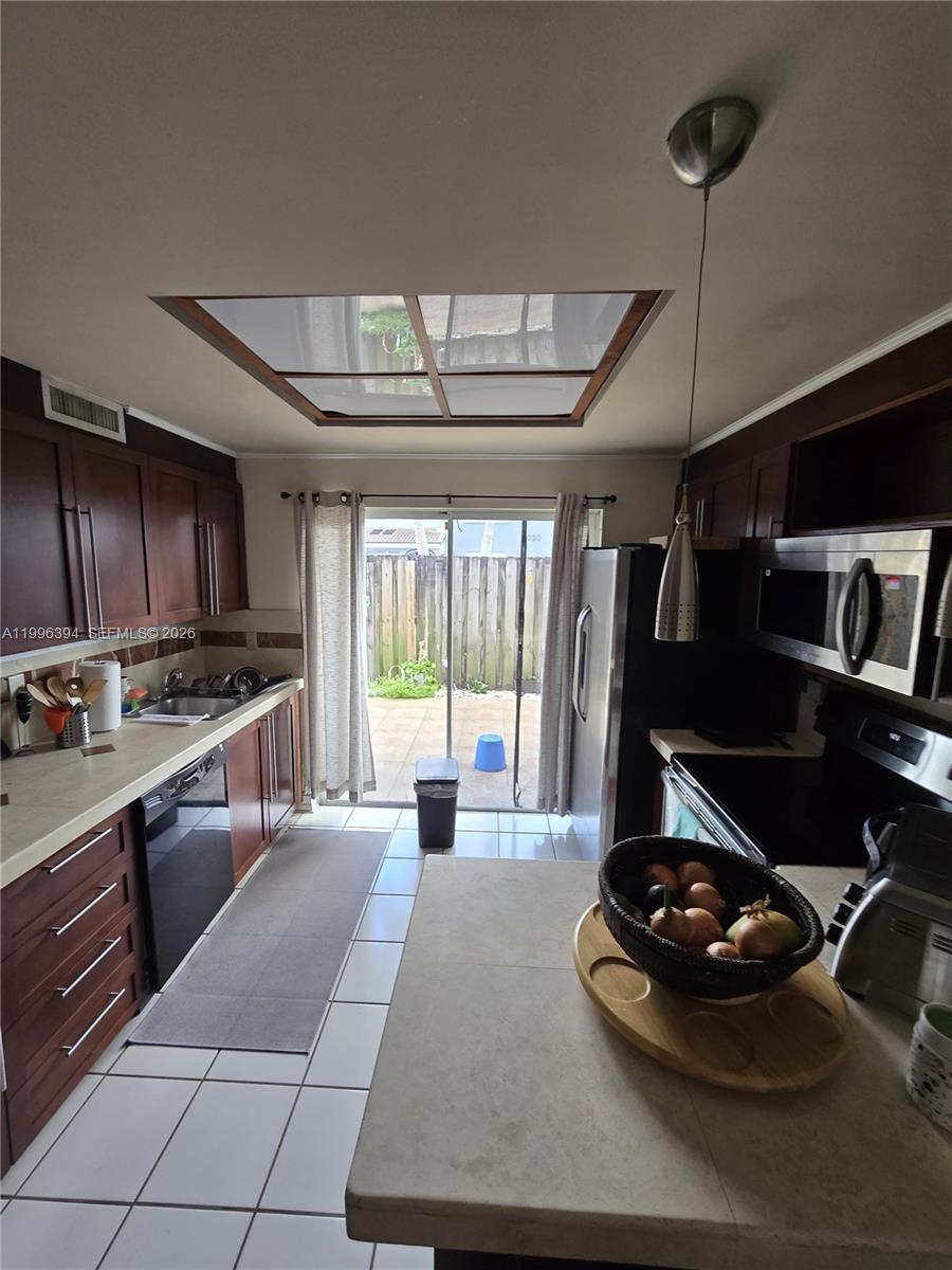 A kitchen features dark wood cabinets, light countertops, a skylight, and a sliding glass door — 7010 NW 173rd Dr # 1901, Hialeah FL 33015, HIALEAH, FL
