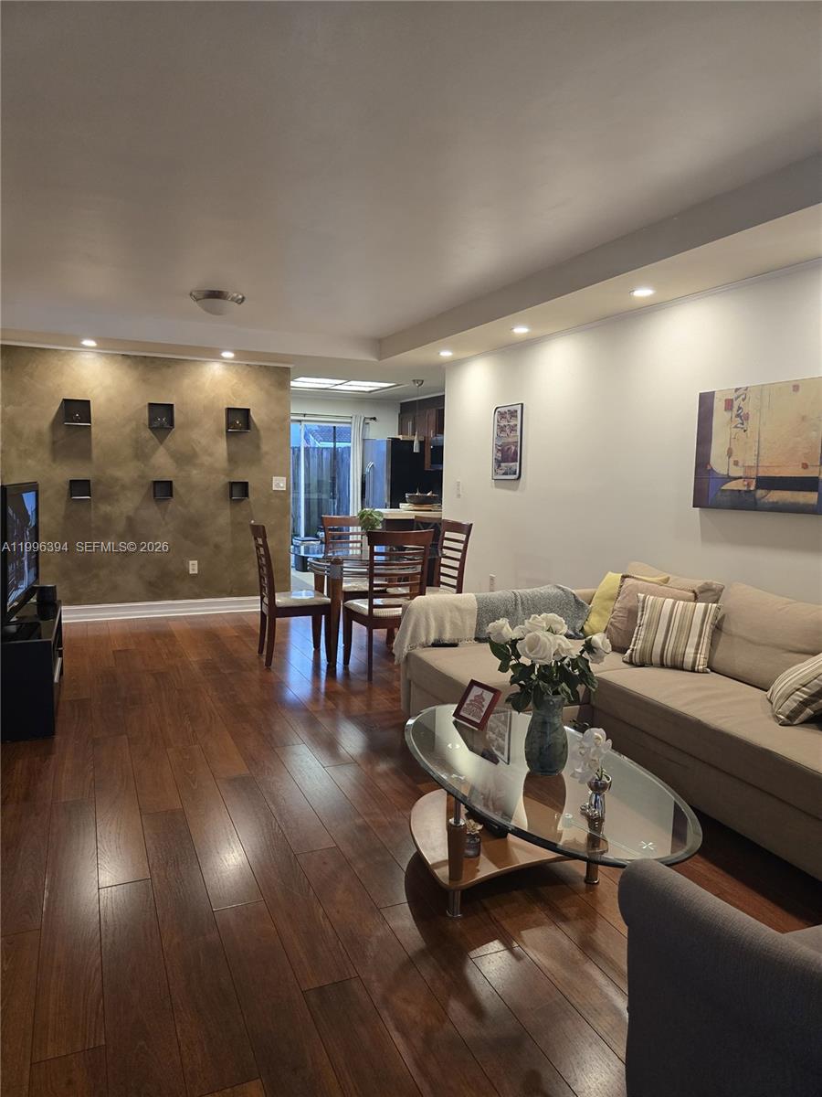 A living room with hardwood floors, a beige sofa, and a textured accent wall — 7010 NW 173rd Dr # 1901, Hialeah FL 33015, HIALEAH, FL