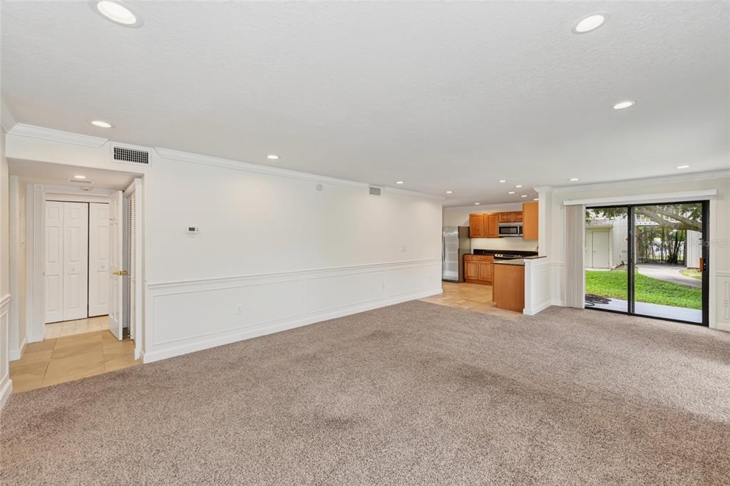 A carpeted living room leads to a kitchen with wood cabinets and a sliding glass door — 2220 BAHIA VISTA STREET UNIT G4, SARASOTA, FL