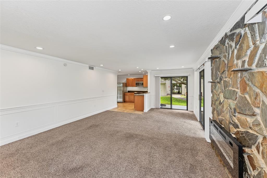 A living room with carpeted floors, a stone fireplace, and an open kitchen in back — 2220 BAHIA VISTA STREET UNIT G4, SARASOTA, FL