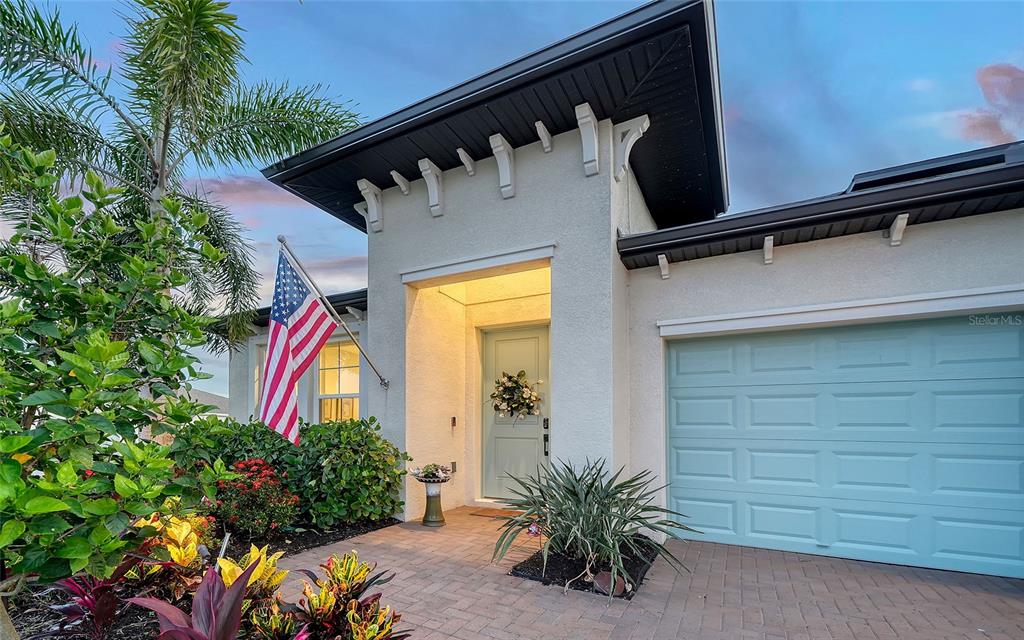 The exterior of a house features a light blue garage door, a matching front door, and landscaping — 12635 NIGHT VIEW DRIVE, SARASOTA, FL
