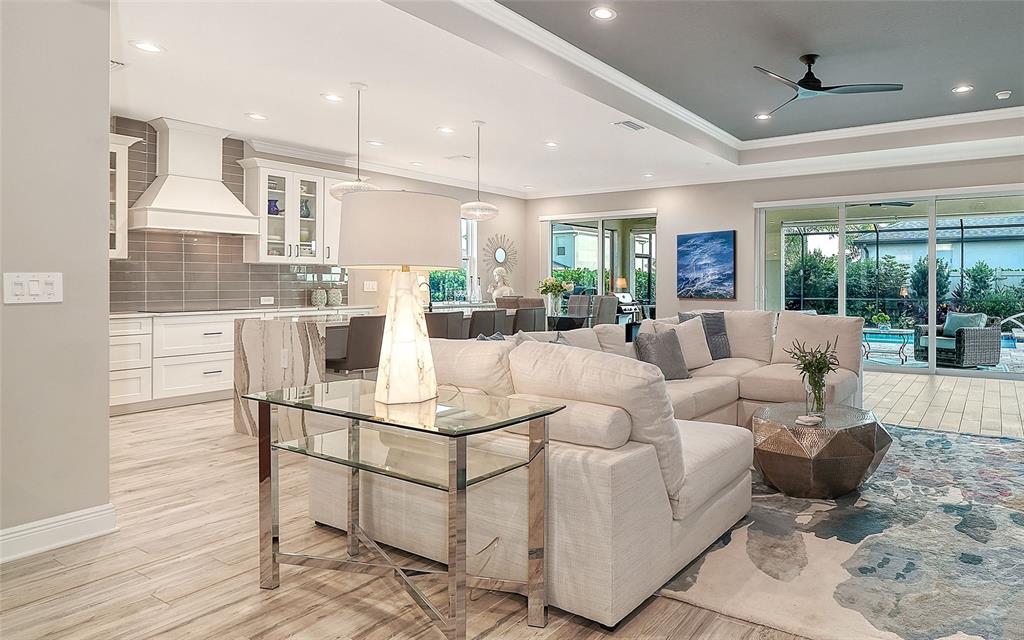 A modern open-concept living room and kitchen featuring white cabinetry, a sectional sofa, and tile flooring — 12635 NIGHT VIEW DRIVE, SARASOTA, FL