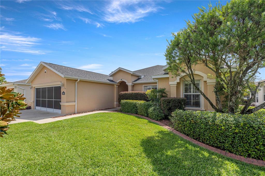 A single-story house with a tan stucco exterior, a two-car garage, and a landscaped yard — 15862 SW 13TH CIRCLE, OCALA, FL