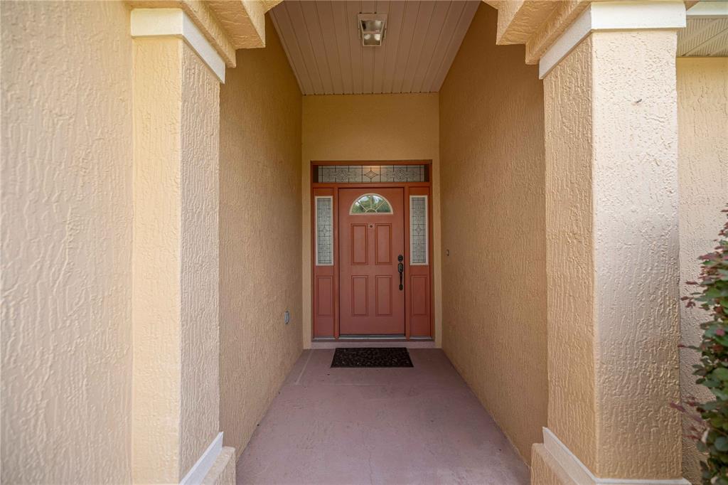 A covered entryway features a reddish-brown front door with sidelights and a transom window — 15862 SW 13TH CIRCLE, OCALA, FL
