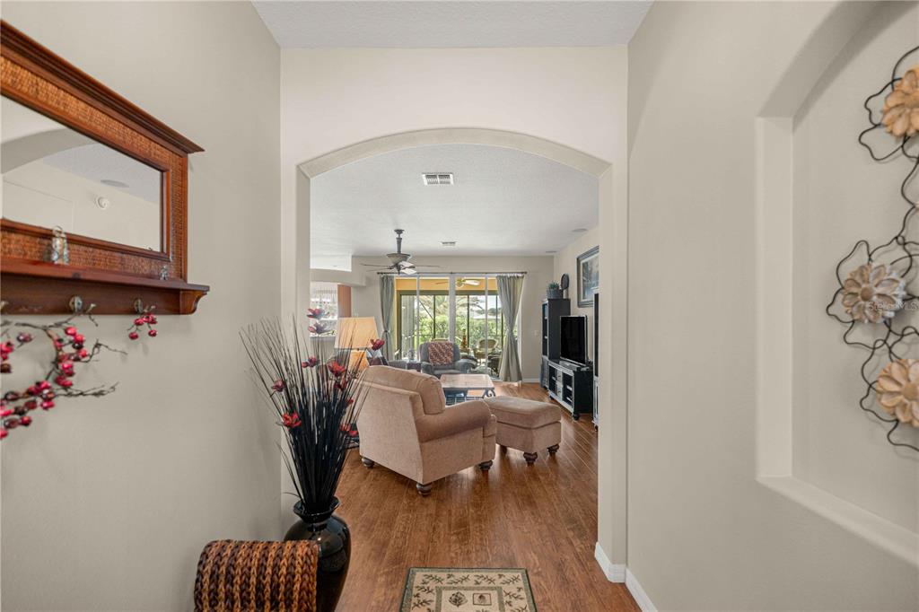A view through an arched entryway into a living room with wood-look flooring — 15862 SW 13TH CIRCLE, OCALA, FL