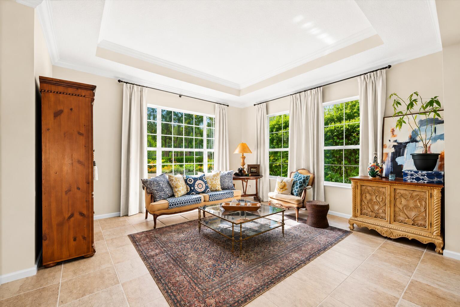 A living room features a tray ceiling, tile flooring, large windows, and traditional furniture — 464 Oriole Lane, Jupiter FL 33458, JUPITER, FL