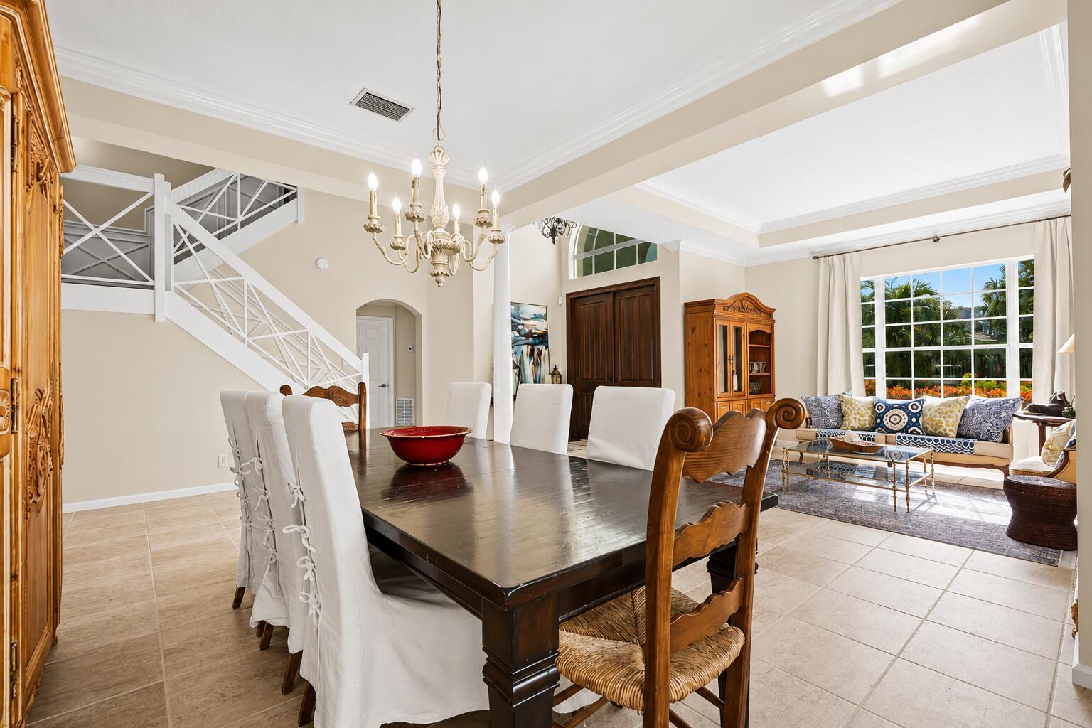 A dining area with a wooden table and white chairs sits beside a living room — 464 Oriole Lane, Jupiter FL 33458, JUPITER, FL