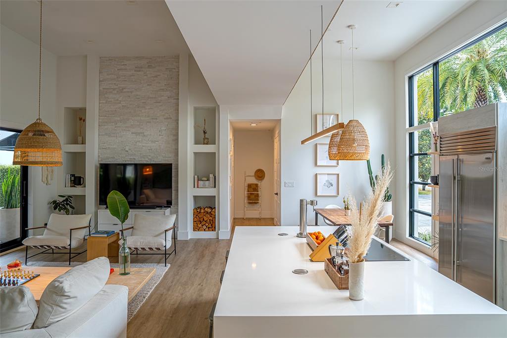 A bright open-concept living room and kitchen featuring a stone fireplace and large windows — 446 MELROSE AVENUE, WINTER PARK, FL