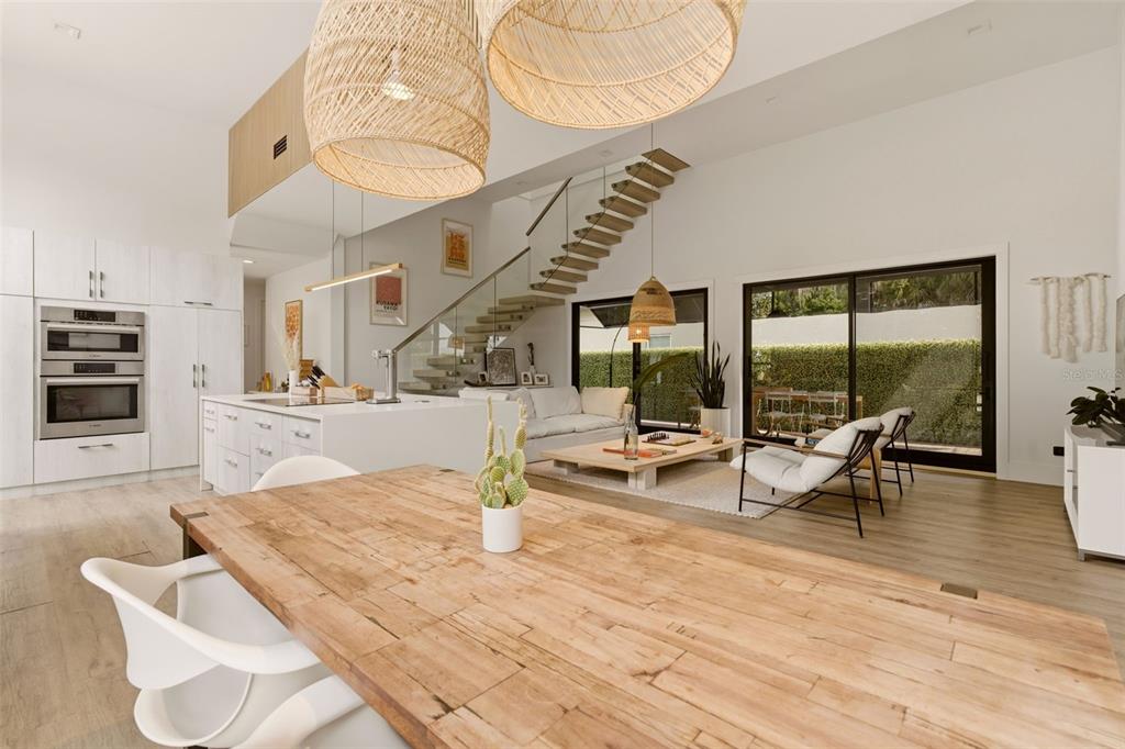 A modern open-concept living space features a kitchen, dining area, and staircase with glass railings — 446 MELROSE AVENUE, WINTER PARK, FL