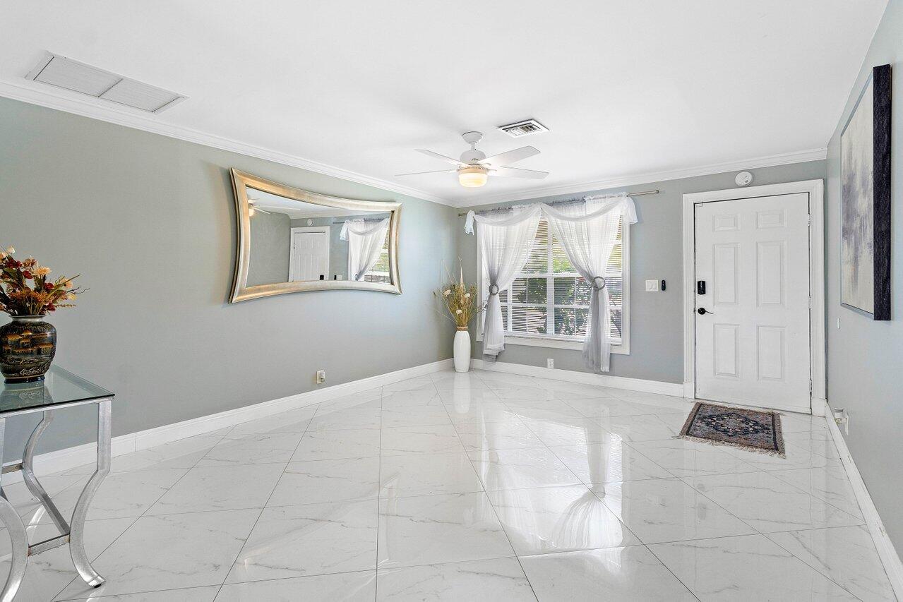 A bright entryway features white marble tile flooring, a large wall mirror, and a front door — 1837 16th Avenue N, FL 33460, FL