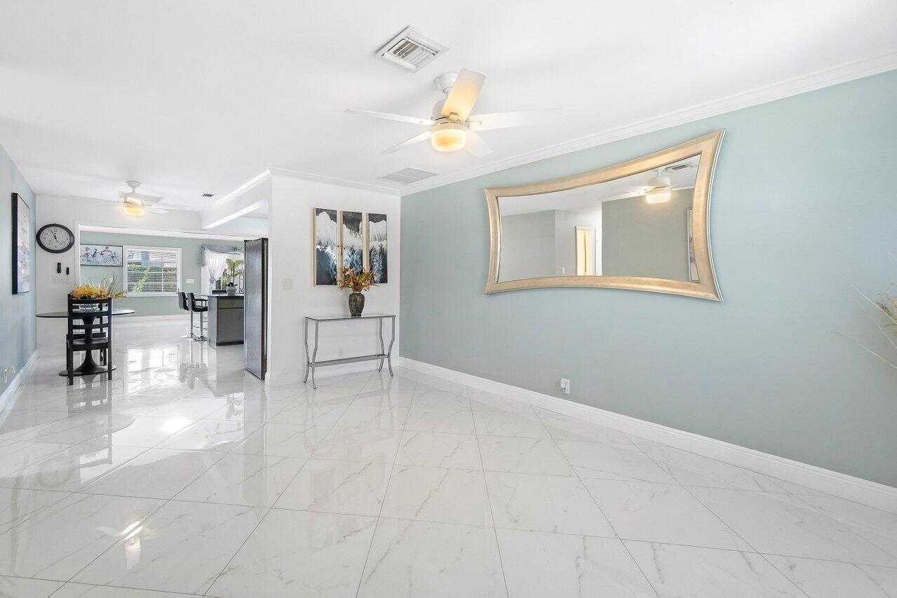 A dining room with white tile floors, a light blue accent wall, and a large mirror — 1837 16th Avenue N, FL 33460, FL