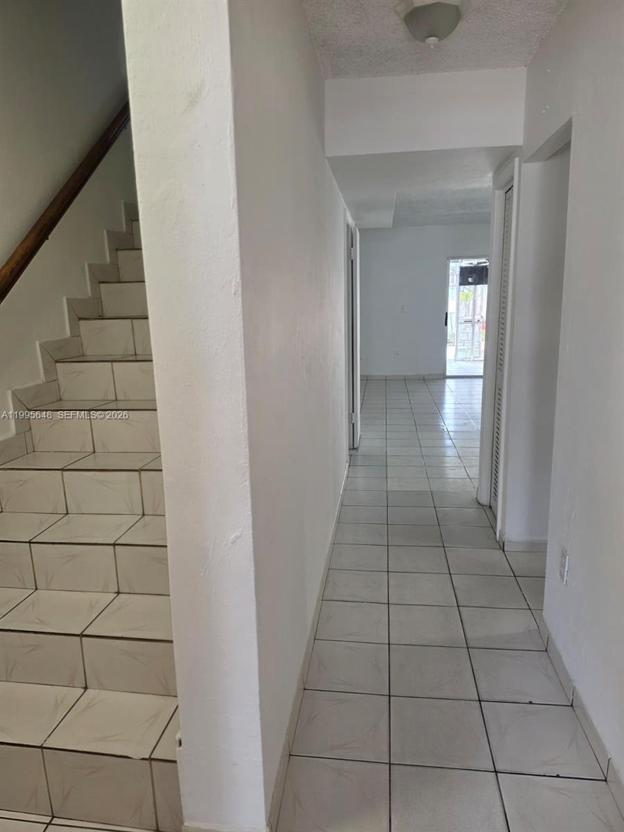 A room with white tile floors, a popcorn ceiling, a chandelier, and an open doorway — 805 W 79th Pl, Hialeah FL 33014, HIALEAH, FL