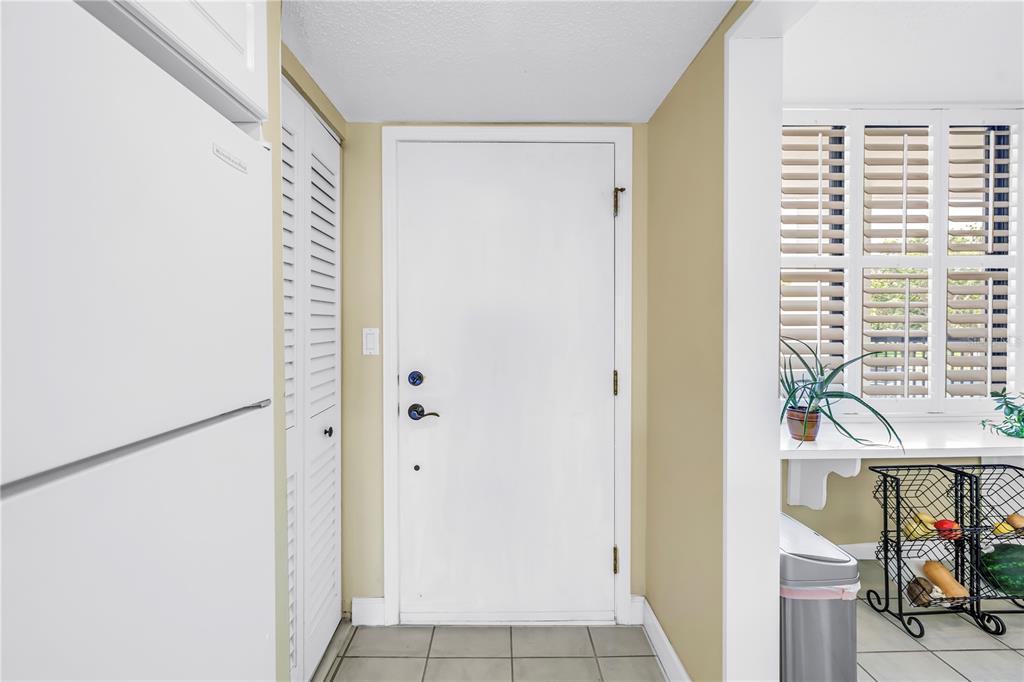 A white front door is centered in a tiled entryway next to a louvered closet — 9425 BLIND PASS ROAD UNIT 207, ST PETE BEACH, FL
