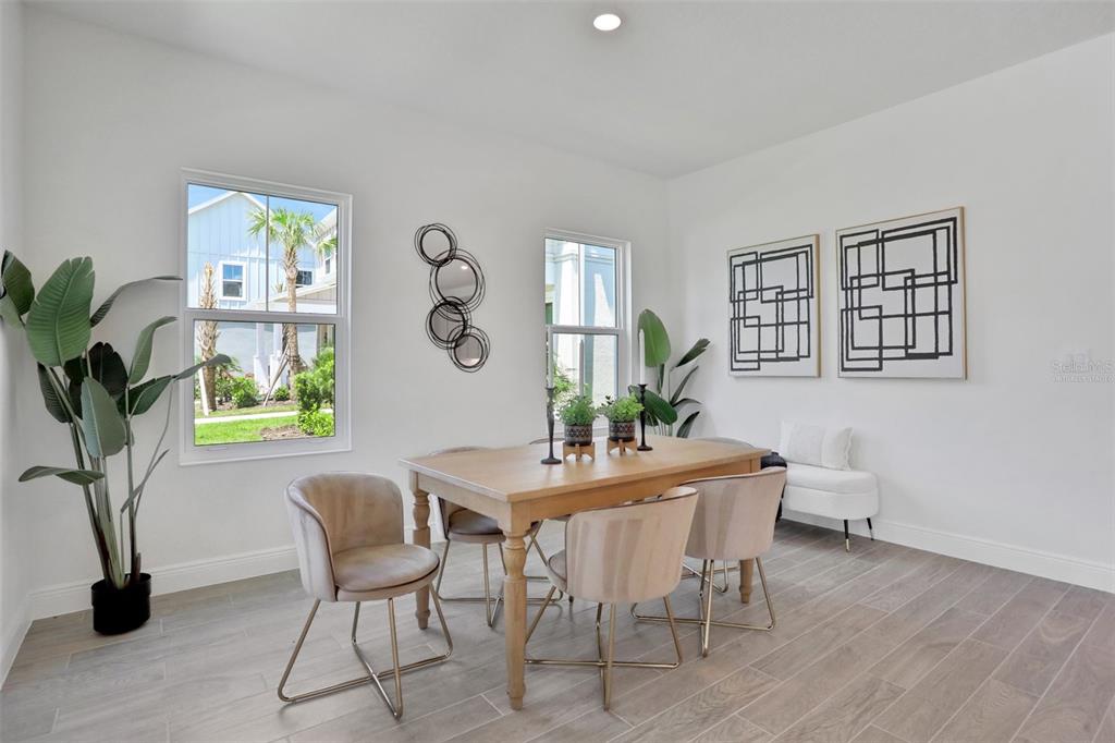 A dining room features a wooden table, four upholstered chairs, two windows, and wall art — 9135 WALCOTT LANE, LAKEWOOD RANCH, FL