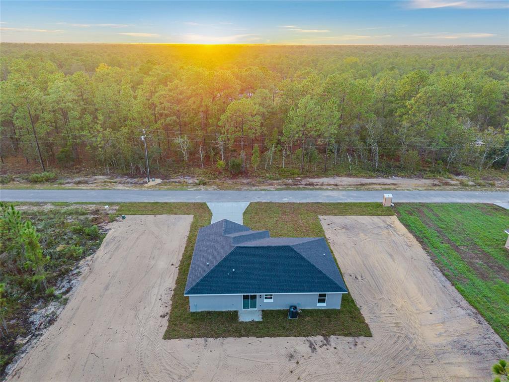 An aerial view shows a newly constructed house with a dark roof surrounded by sandy soil — 22632 SW NAUTILUS BOULEVARD, DUNNELLON, FL