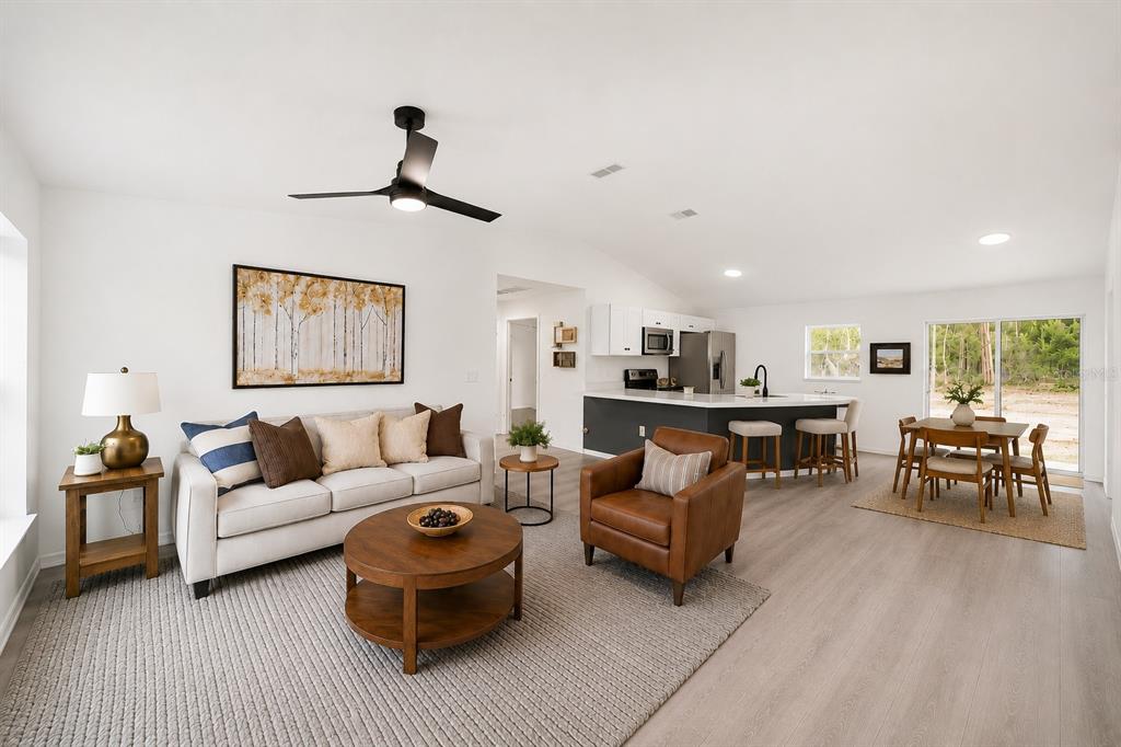 An open-concept living room and kitchen with light wood floors and a neutral color palette — 22632 SW NAUTILUS BOULEVARD, DUNNELLON, FL