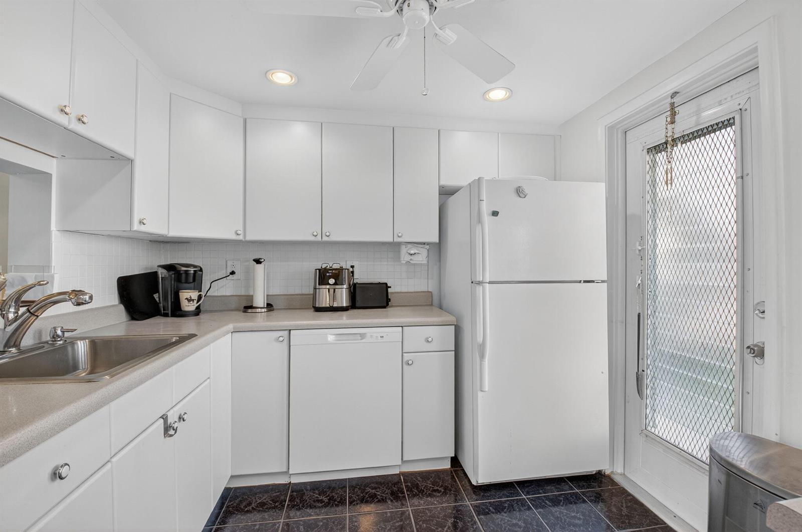 A kitchen with white cabinets, a white refrigerator, a dishwasher, and dark tiled flooring — 2152 NE 1st Way # 101, Boynton Beach FL 33435, BOYNTON BEACH, FL