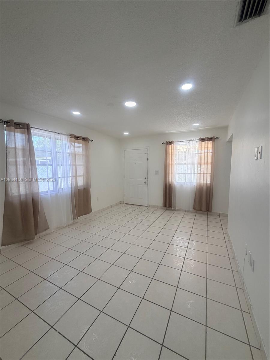 An empty room features white tiled floors, recessed lighting, and windows with brown curtains — 3821 SW 89th Ct, Miami FL 33165, MIAMI, FL
