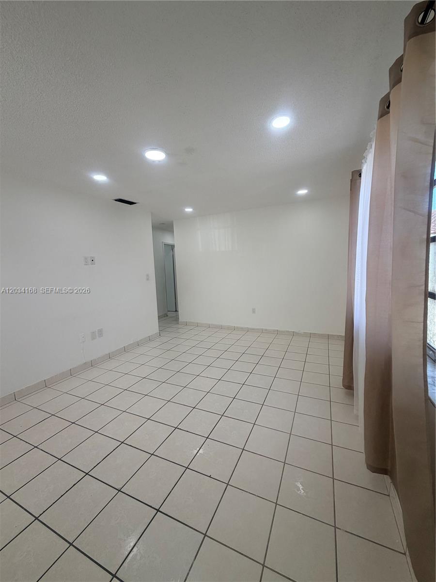 An empty room features white walls, recessed ceiling lights, and light-colored square floor tiles — 3821 SW 89th Ct, Miami FL 33165, MIAMI, FL