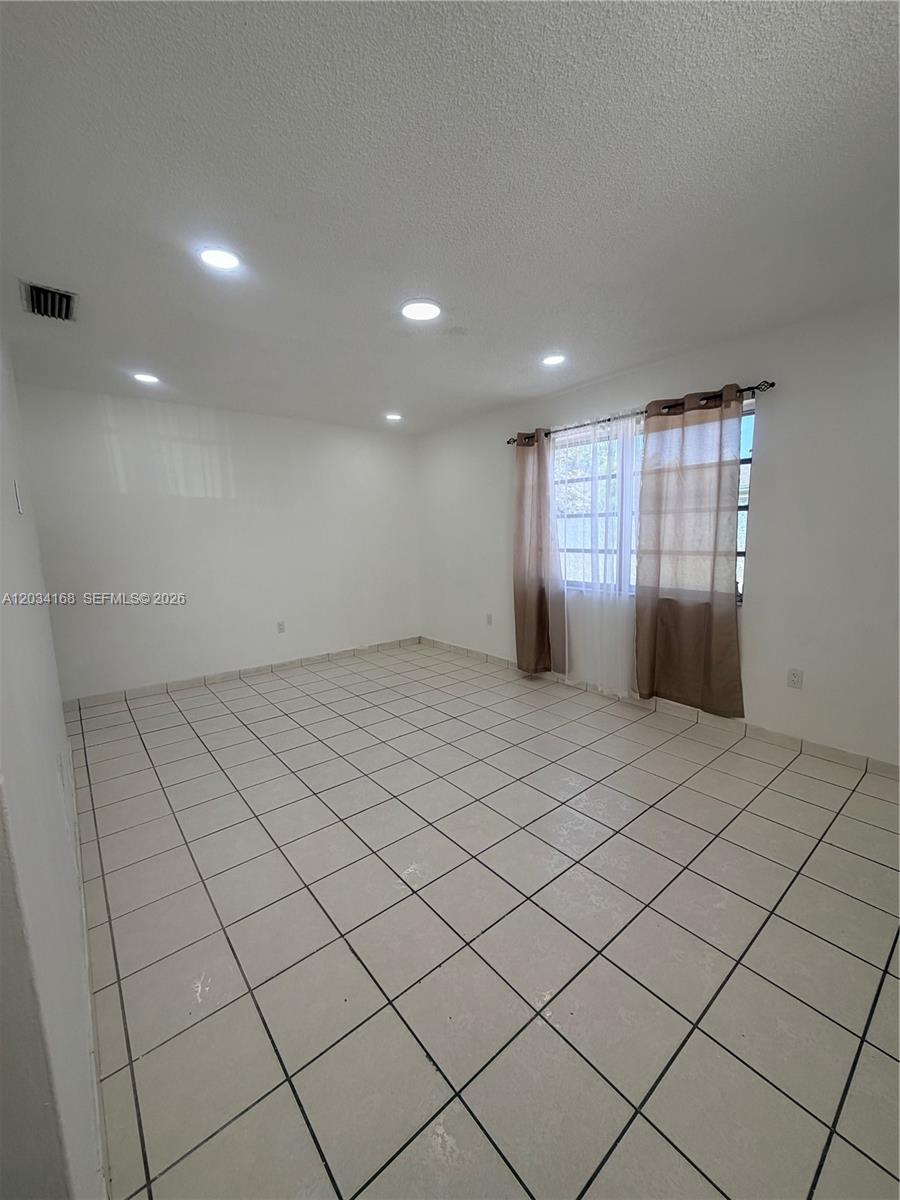 An empty room features white walls, recessed ceiling lights, and light-colored square floor tiles — 3821 SW 89th Ct, Miami FL 33165, MIAMI, FL