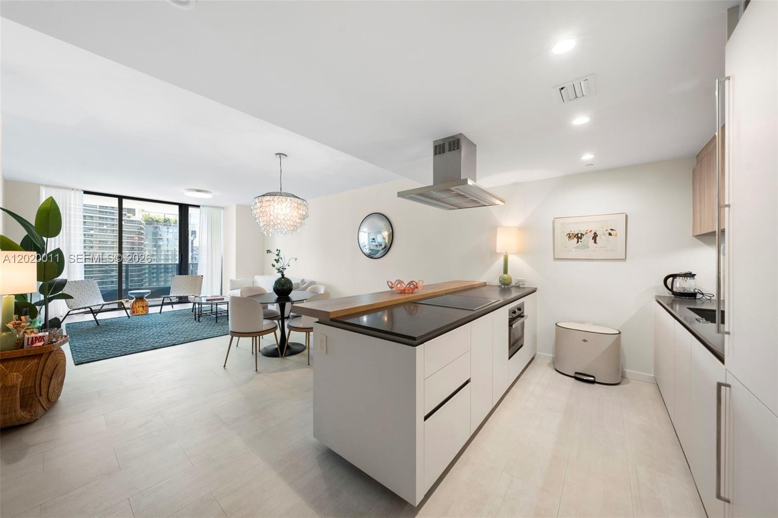 A modern open-concept kitchen and living area with white cabinetry and a central island — 1000 Brickell Plz # 4014, Miami FL 33131, MIAMI, FL