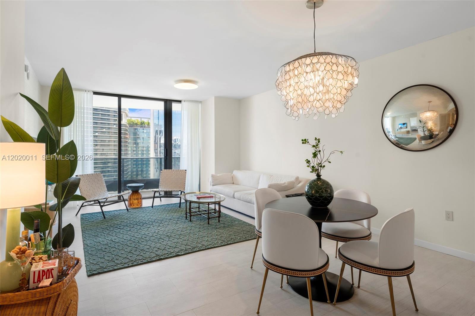 A living and dining room features a white sofa, round table, and a large chandelier — 1000 Brickell Plz # 4014, Miami FL 33131, MIAMI, FL