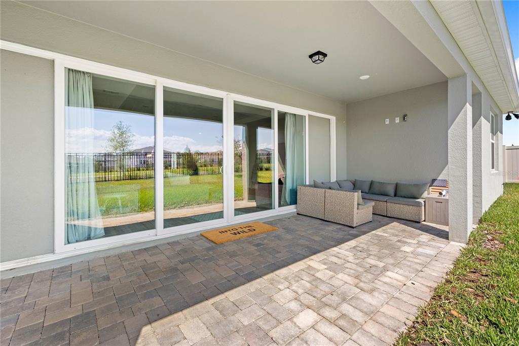 A paved patio features a sectional sofa, a doormat, and large sliding glass doors — 5269 FOOTHILLS PRESERVE LOOP, MOUNT DORA, FL