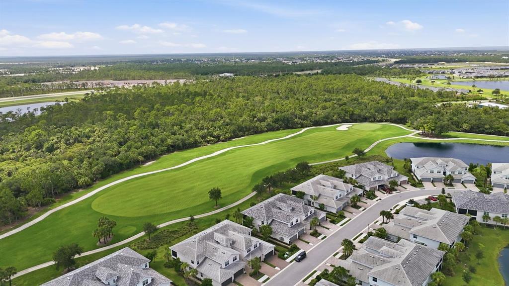 An aerial view shows a golf course fairway adjacent to a residential neighborhood with houses — 14648 SYCAMORE COURT UNIT 3012, PUNTA GORDA, FL
