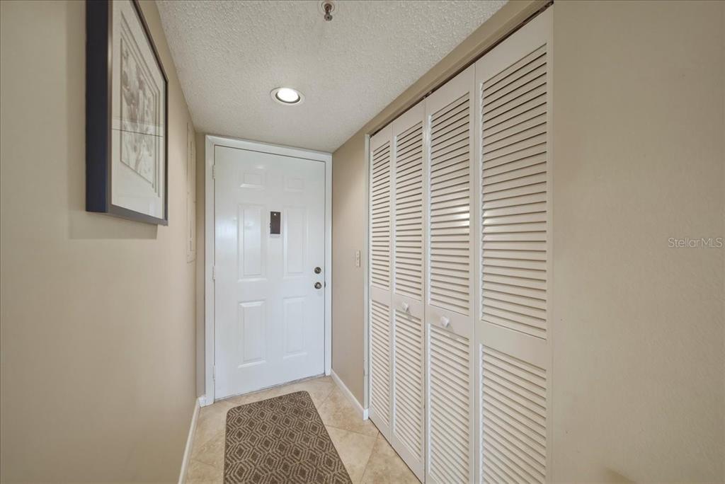 An entryway features a white front door, a louvered closet, and tile flooring — 835 WEXFORD BOULEVARD UNIT 301, VENICE, FL