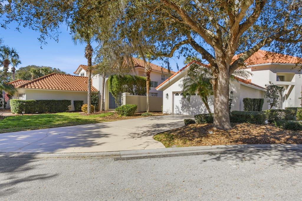 A single-story house with a tile roof, a concrete driveway, and large oak trees — 13 MADEIRA COURT, PALM COAST, FL