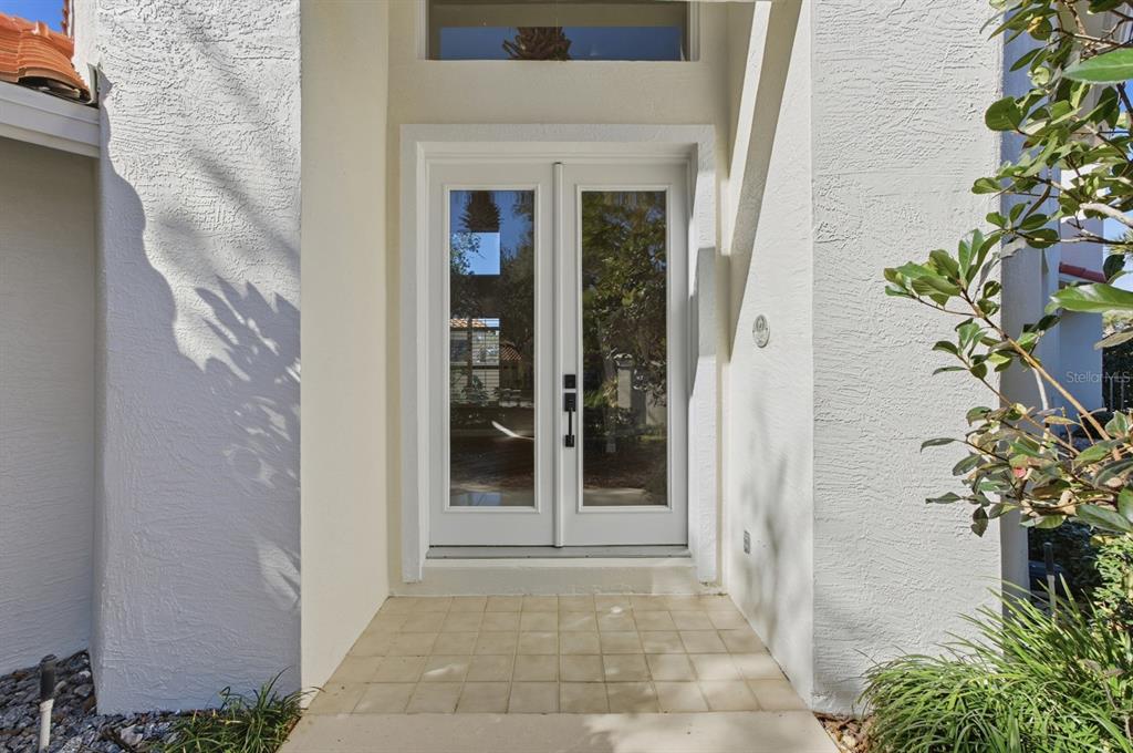 A white double front door with glass panels is set within a stucco entryway — 13 MADEIRA COURT, PALM COAST, FL